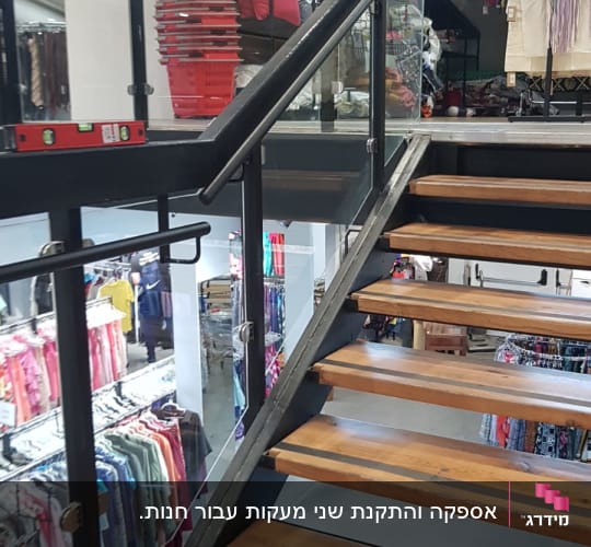 מדרגות ממתכת עם מדרכי עץ ומעקה מתכת וזכוכית בחנות